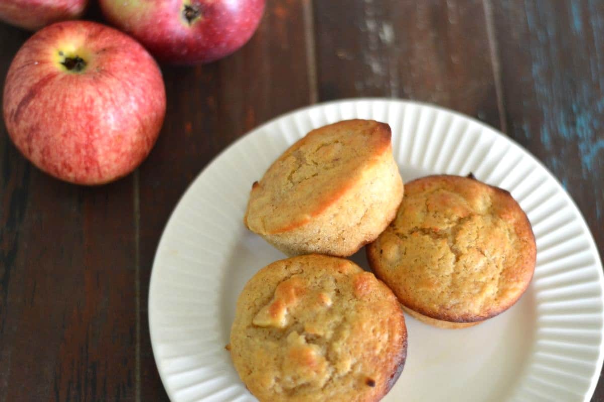 white plate with 3 apple cinnamon muffins. Apples garnished to the side.